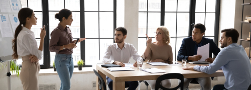 Groupe de personnes en réunion autour d’une table dans un bureau lumineux