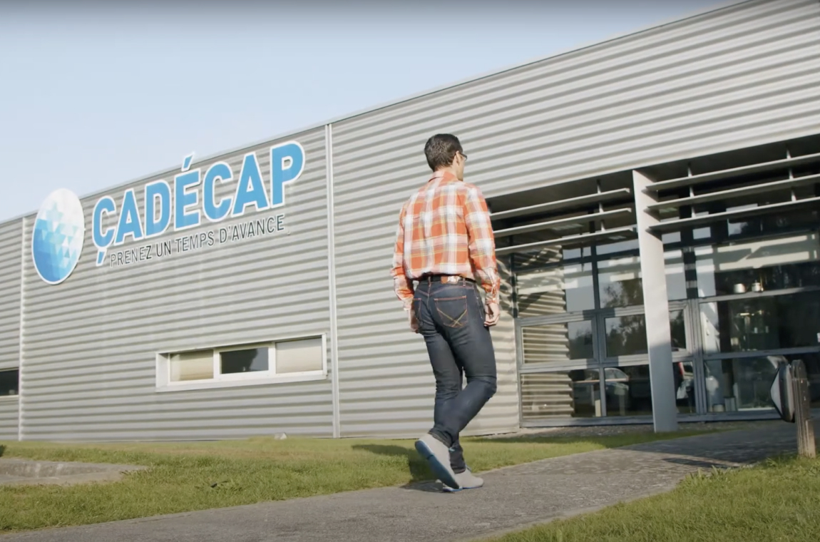 Personne marchant vers un bâtiment gris portant l’enseigne “CADÉCAP”