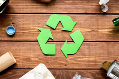 Symbole de recyclage vert entouré de déchets triés sur une table en bois