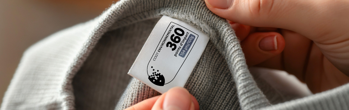 Étiquette d’impact environnemental affichant le score 360 sur un vêtement gris tenu entre deux mains